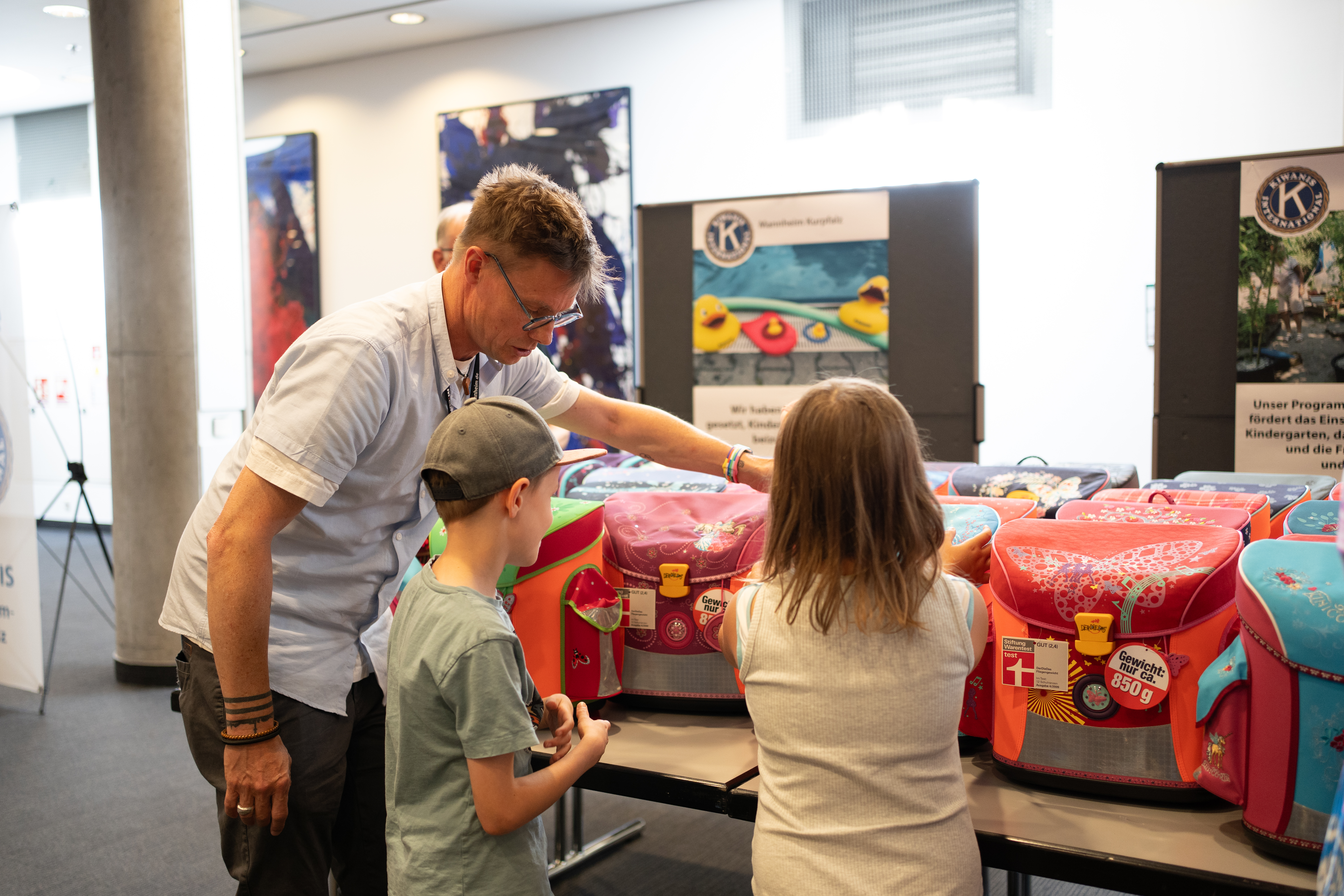 Ein Mann übergibt einem Kind einen Schulranzen